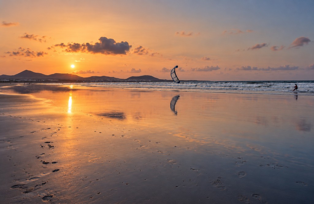 Plaża o zachodzie — kitesurfer i odbicia